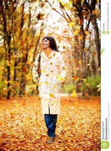 Woman walking outdoors amongst autumn falling leaves